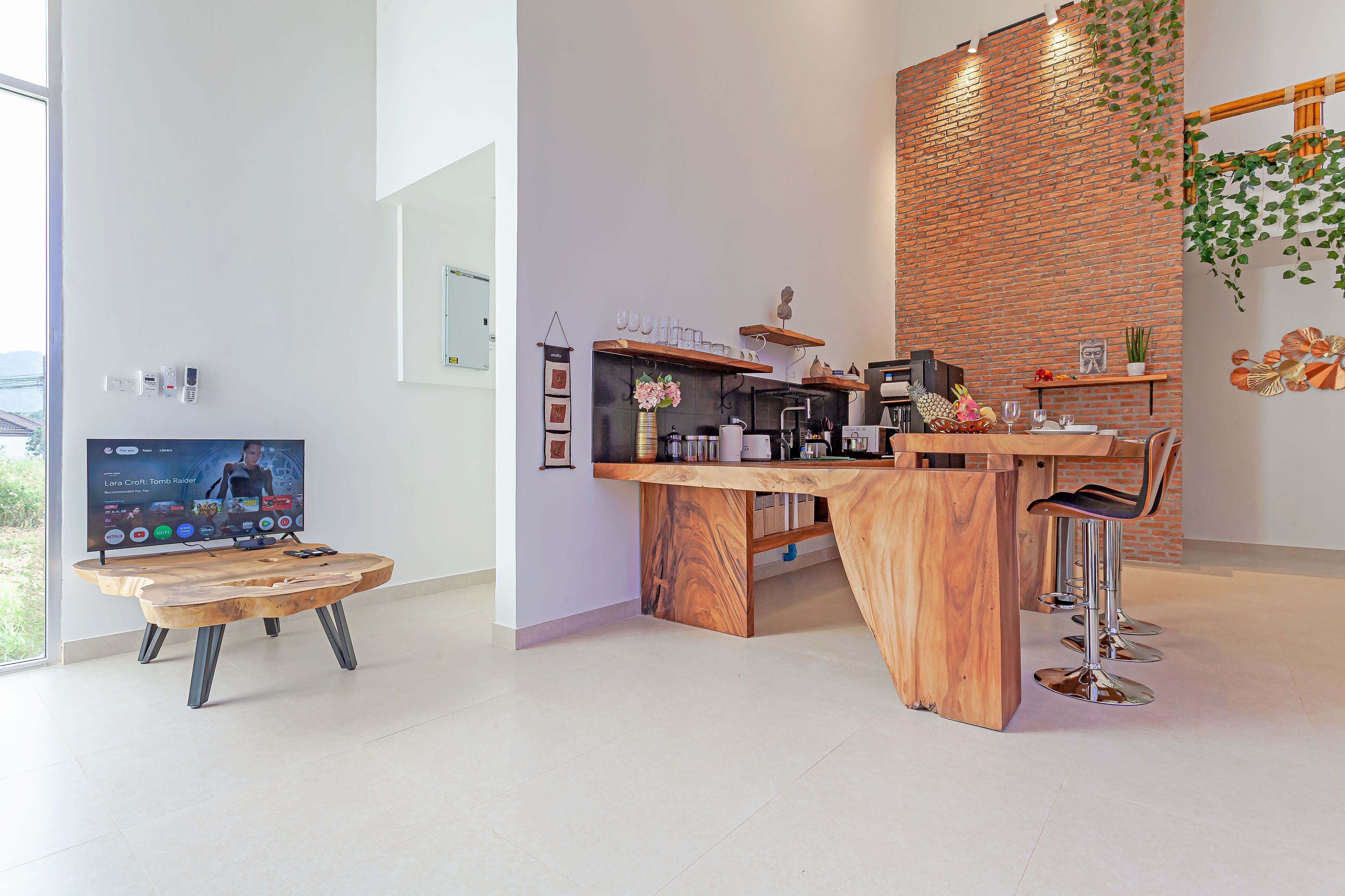 A modern kitchen with a wooden island, bar stools, and a brick accent wall.