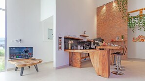 A modern kitchen with a wooden island, bar stools, and a brick accent wall. - Tom Star Pool Villa Layan 3BR Large pool, mountain view for the rooftop (ตำบล ศรีสุนทร)
