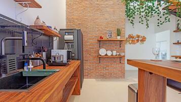 A modern kitchen with a brick wall, wooden shelves, and a black countertop.