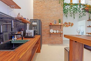 Eine moderne Küche mit Backsteinwand, Holzböden und einer schwarzen Arbeitsplatte.