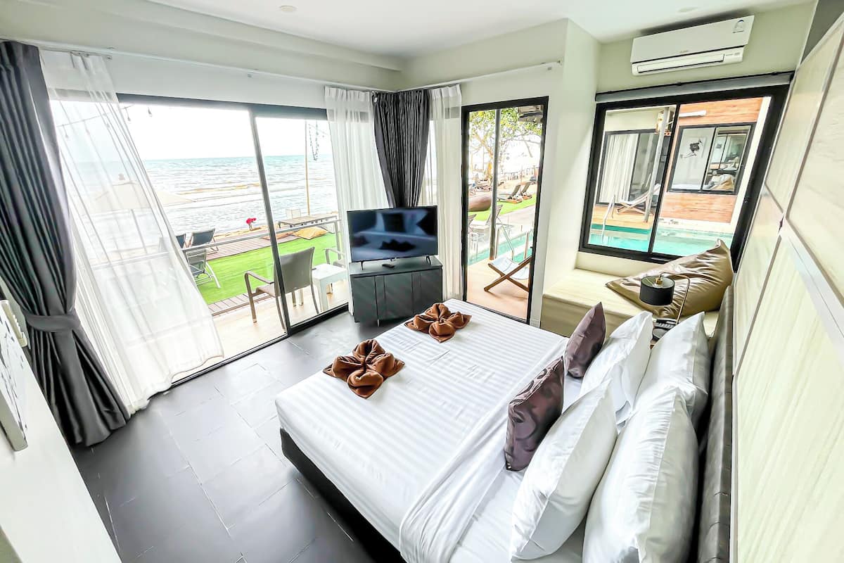 A hotel room with a large bed, a TV, and a balcony with a pool view.