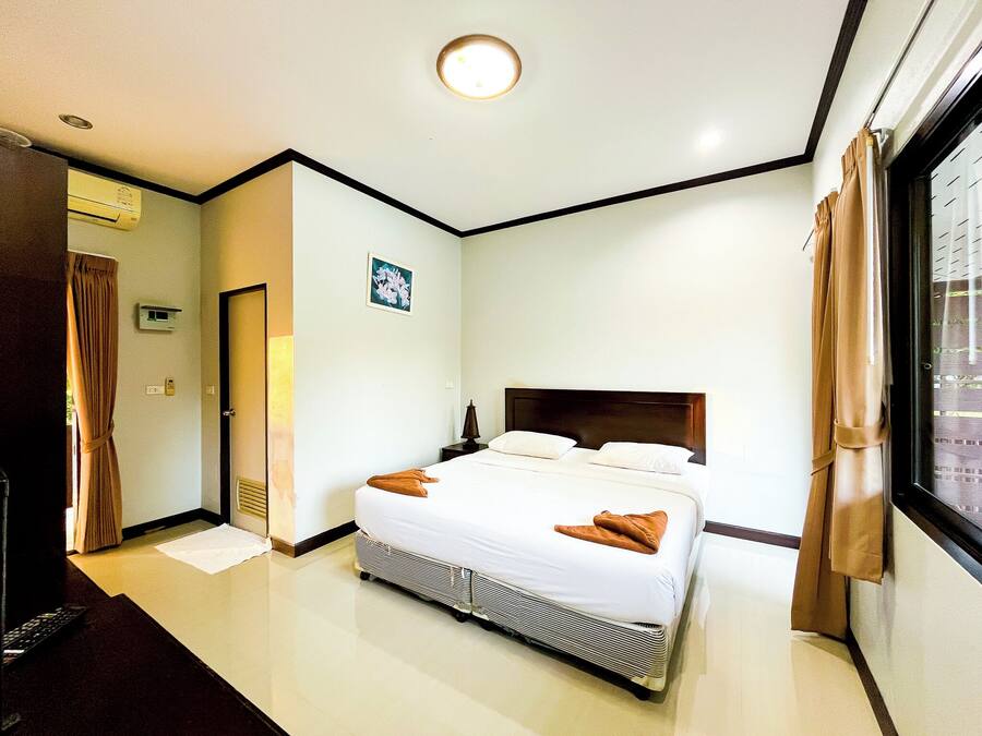 Ein Hotelzimmer mit Bett, Nachttisch, Fenster mit Vorhängen und einer Tür.