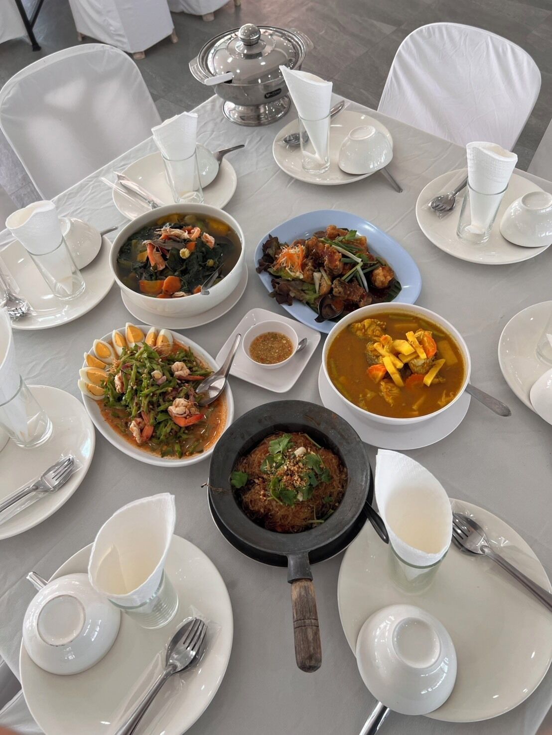 A table set with various dishes, including seafood, salads, and soups, in a clean and organized dining area.