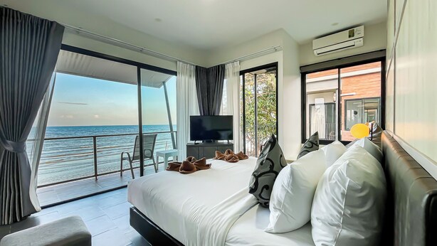 Una habitación de hotel moderna con una cama grande, televisión y balcón con vista al mar.