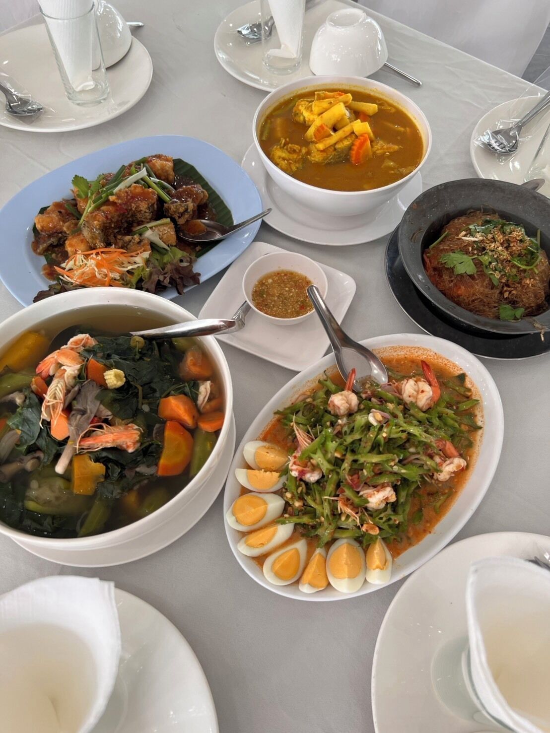 A table set with various dishes including seafood, vegetables, and a soup.