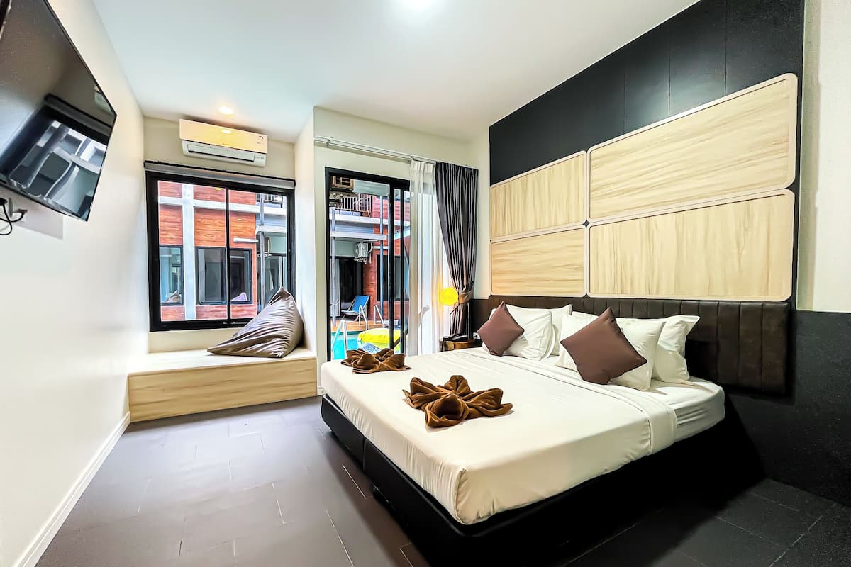 A modern hotel room with a large bed, a seating area by the window, and a view of the outside.