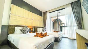 Habitación de hotel con dos camas, un espejo grande, un televisor y un balcón con cortinas.