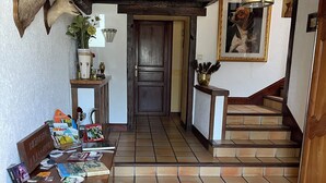 A hallway with a wooden table, a mounted deer head, and a staircase.