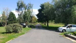 A paved driveway leading to a building with a car parked on the right.