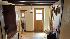 A hallway with a wooden door, tiled floor, and a small table with items on it.