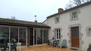 A patio area with a tiled floor, a table with chairs, and a stone wall.