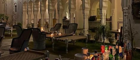 An outdoor seating area with tables, chairs, and a variety of bottles.
