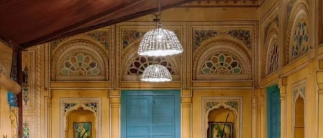A room with a blue door, wooden furniture, decorative vases, and a hanging light fixture.