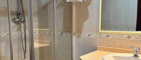 A modern bathroom with a glass-enclosed shower, a white sink, and a mirror above the sink.
