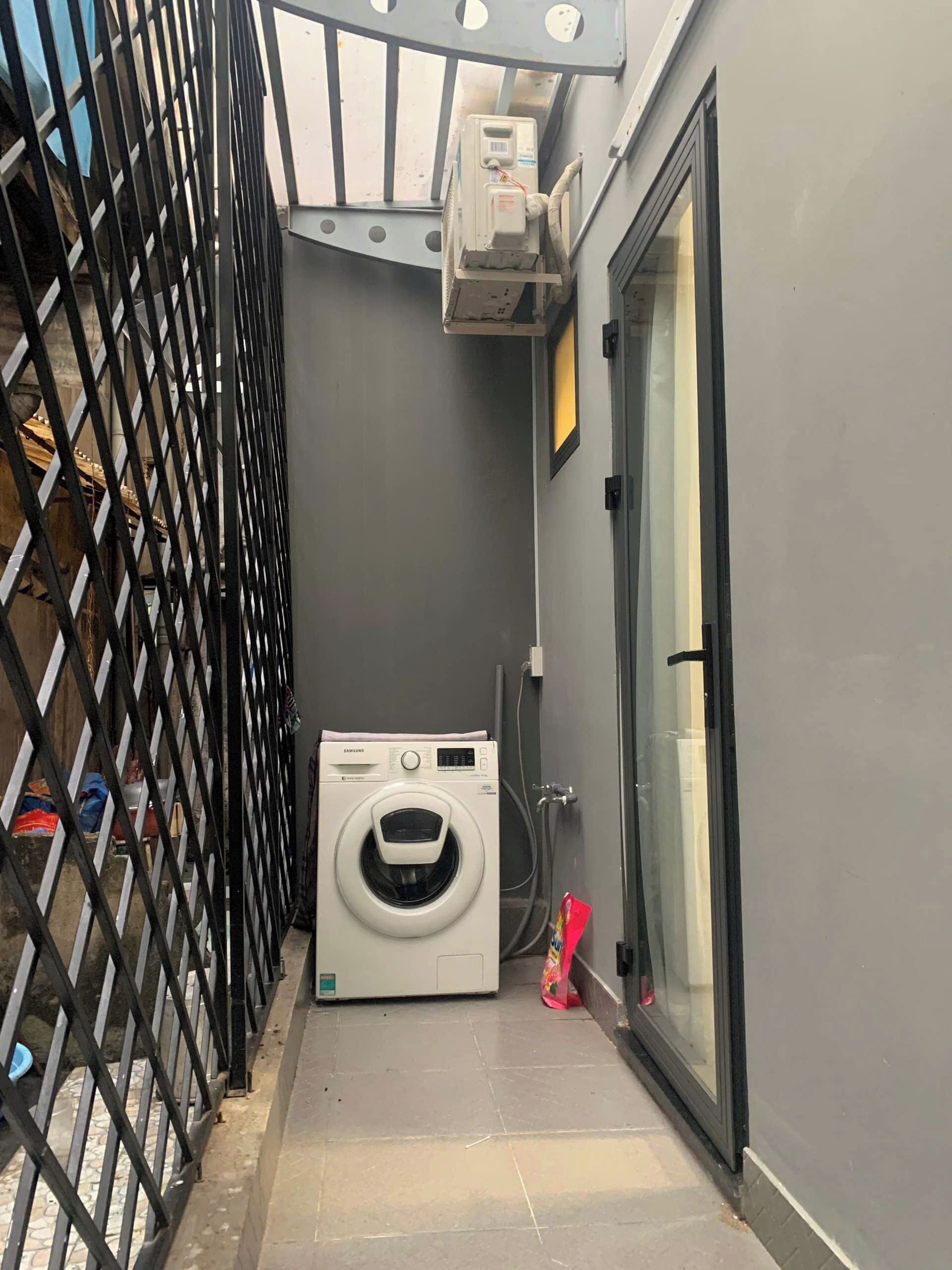 A laundry area with a washing machine, a metal gate, and a glass door.