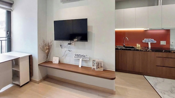Een moderne keuken met een inbouwoven, een magnetron en een spoelbak. Er is een flatscreen televisie aan de muur bevestigd boven een houten bank.