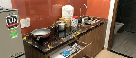 A compact kitchen with a Sharp refrigerator, a sink, and a countertop with various kitchen items.