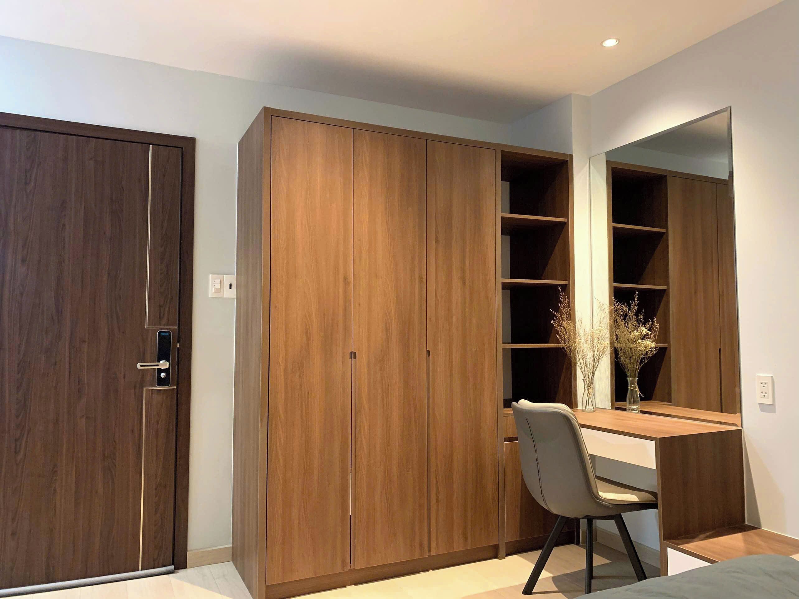 A bedroom with a wardrobe, a desk, and a mirror.