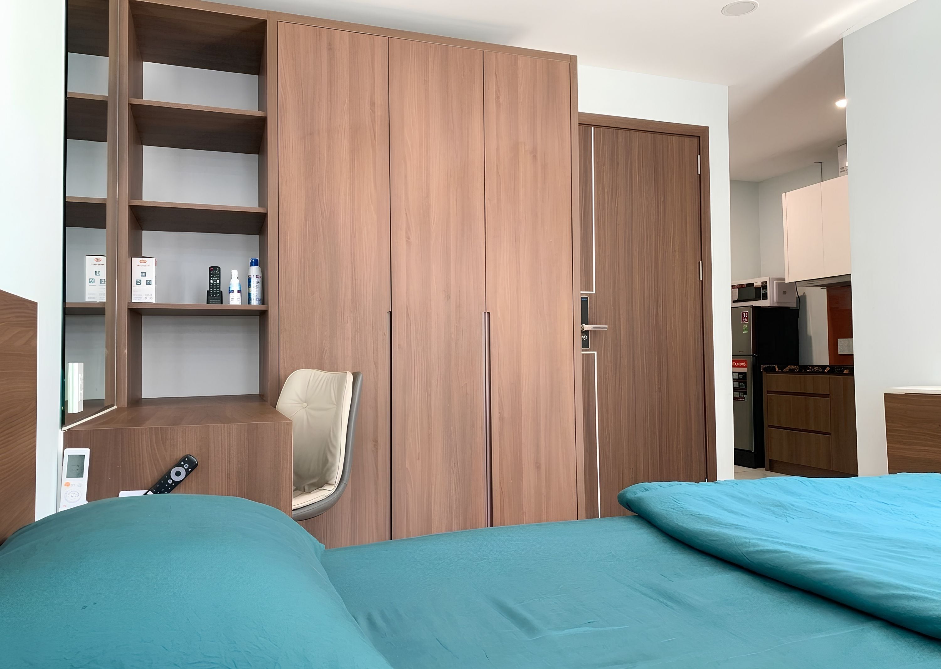Ein Schlafzimmer mit Bett, Stuhl, Kleiderschrank und einer Küchenzeile.