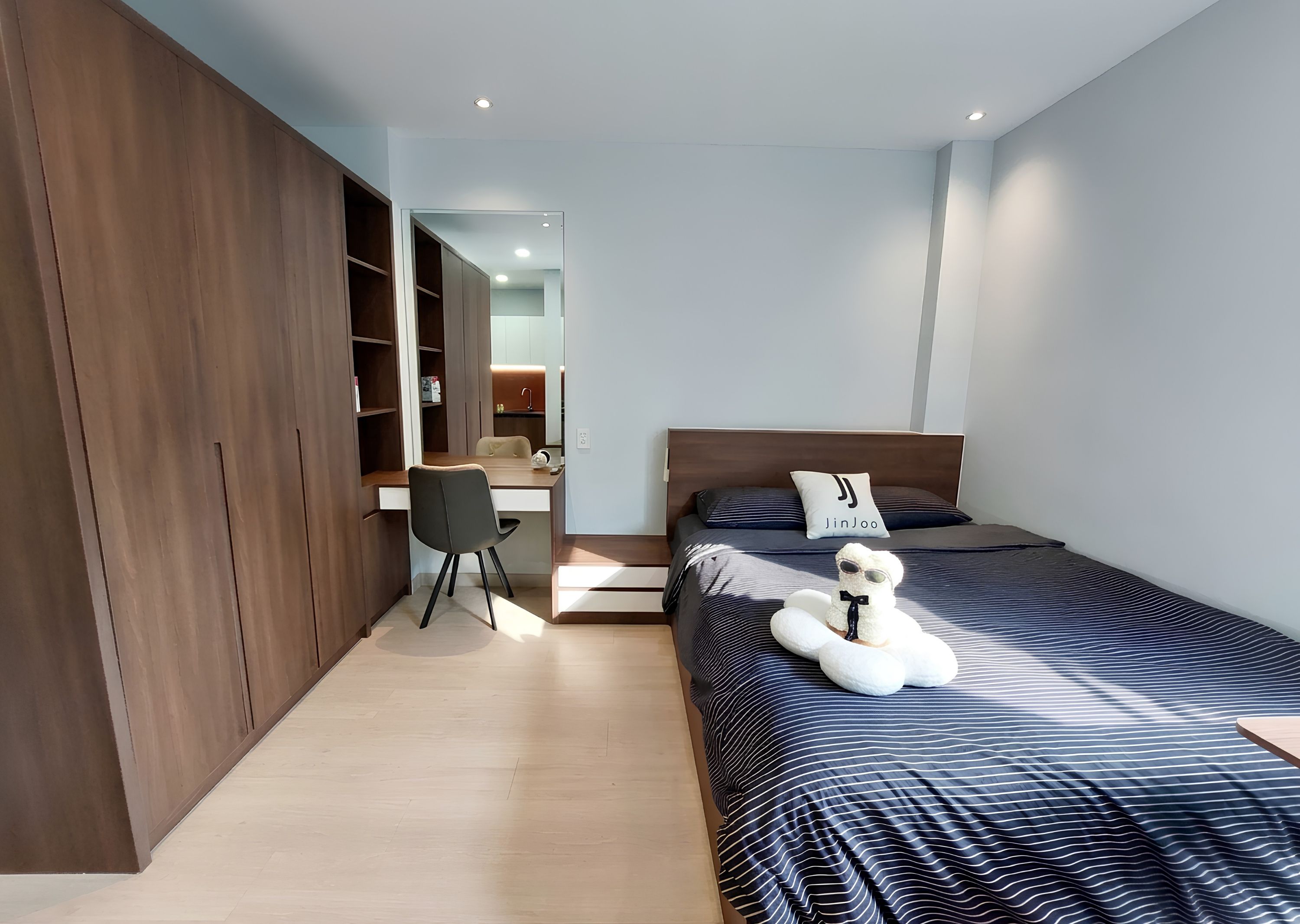 A modern bedroom with a bed, a desk, and a wardrobe.