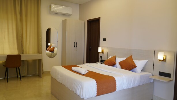 A hotel room with a bed, a desk, a chair, a wardrobe, and a mirror. - Ustay (Hyderabad)