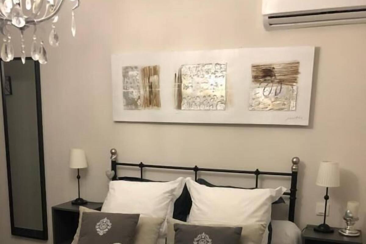 Une chambre à coucher bien rangée, avec un lit, des tables de chevet et des œuvres d’art accrochées au mur.