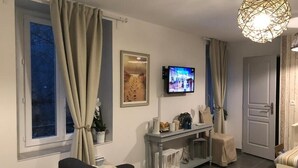 Ein Wohnzimmer mit einer Couch, einem Couchtisch, einem an der Wand befestigten Fernseher und einer dekorativen Leuchte.
