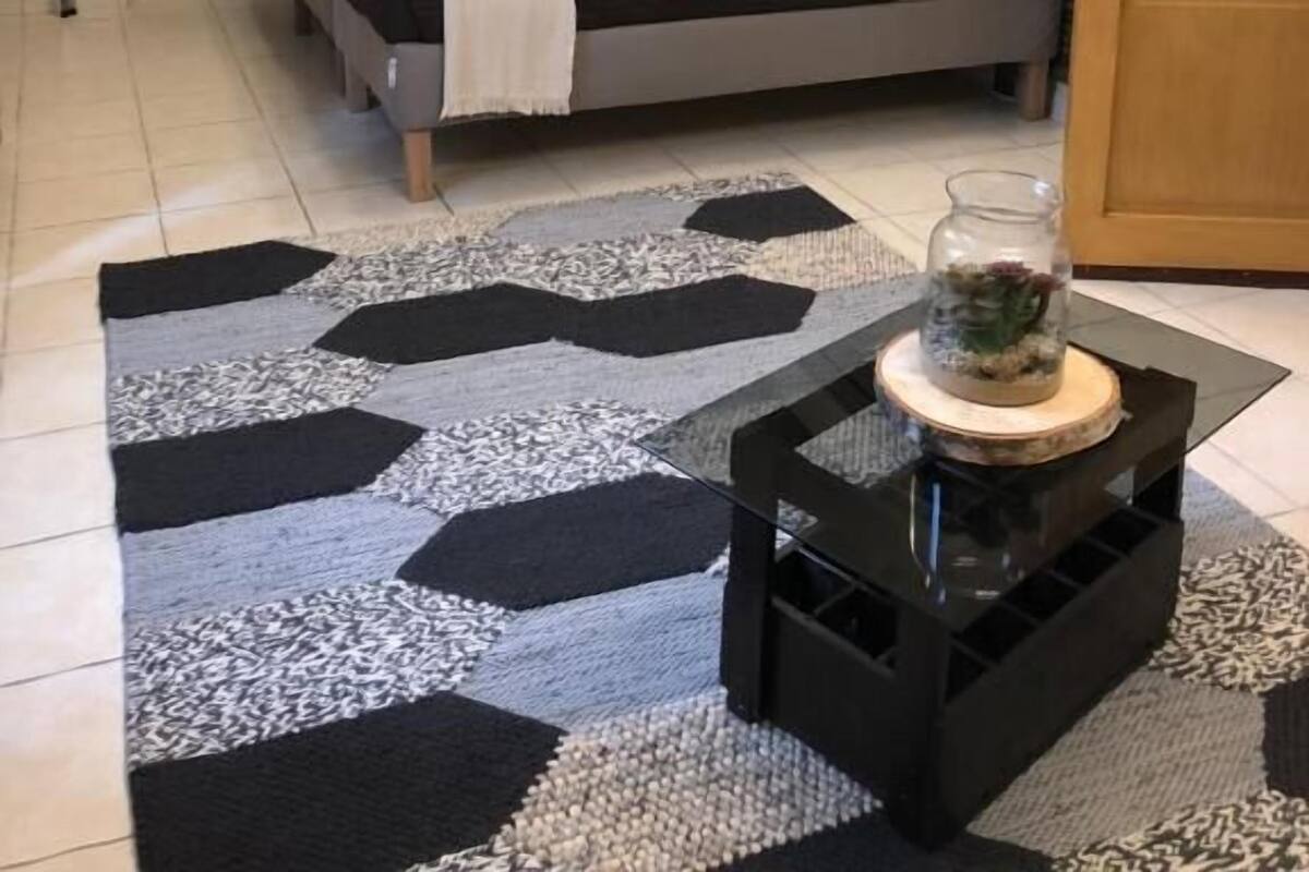Une chambre à coucher comprenant un lit, un lustre, une table de chevet, une lampe, une petite table ornée d’un objet décoratif et une armoire.