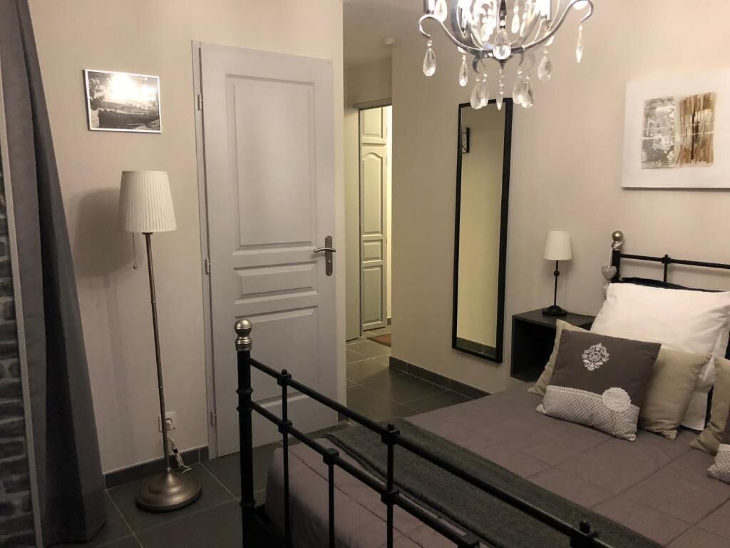 Un dormitorio con cama, mesita de noche, lámpara y espejo.
