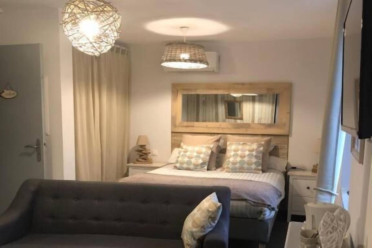 Une pièce confortable avec un lit, un canapé, une petite table et un bureau avec une lampe.