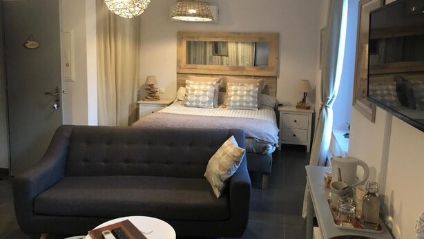 Ein Schlafzimmer mit einem großen Bett, einem Schlafsofa, einem Nachttisch und einer hängenden Deckenleuchte.
