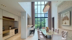 A modern kitchen with a dining area, large windows, and a chandelier. - Baan Wang Tan 1 Luxury Pool Villa, Chiang Mai (Chiang Mai)