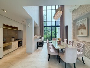 A modern kitchen with a dining area, large windows, and a chandelier. - Baan Wang Tan 1 Luxury Pool Villa, Chiang Mai (Chiang Mai)