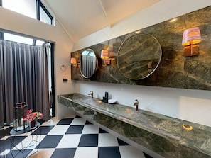 Un baño moderno con tocador de mármol, dos lavamanos y un espejo grande.
