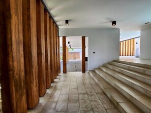 A modern interior with a wooden columned corridor leading to a staircase. - Baan Wang Tan 1 Luxury Pool Villa, Chiang Mai (Chiang Mai)