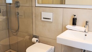 Moderni kylpyhuone, jossa on suihku, wc ja pesuallas.