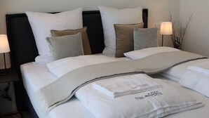 A neatly made bed with white linens and multiple pillows, including striped and solid colors, in a modern hotel room. - Munich Finest Apartments 19 by Interhome (Munich)