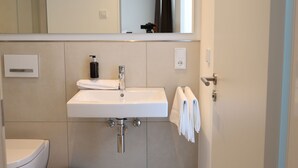 A modern bathroom with a white sink, a mirror, and a toilet. - Munich Finest Apartments 19 by Interhome (Munich)