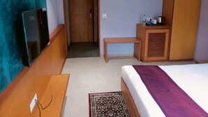 A hotel room with a bed, a television, a desk, a wardrobe, and a door leading to another room. - Hotel Rajputana International Raipur (Raipur)