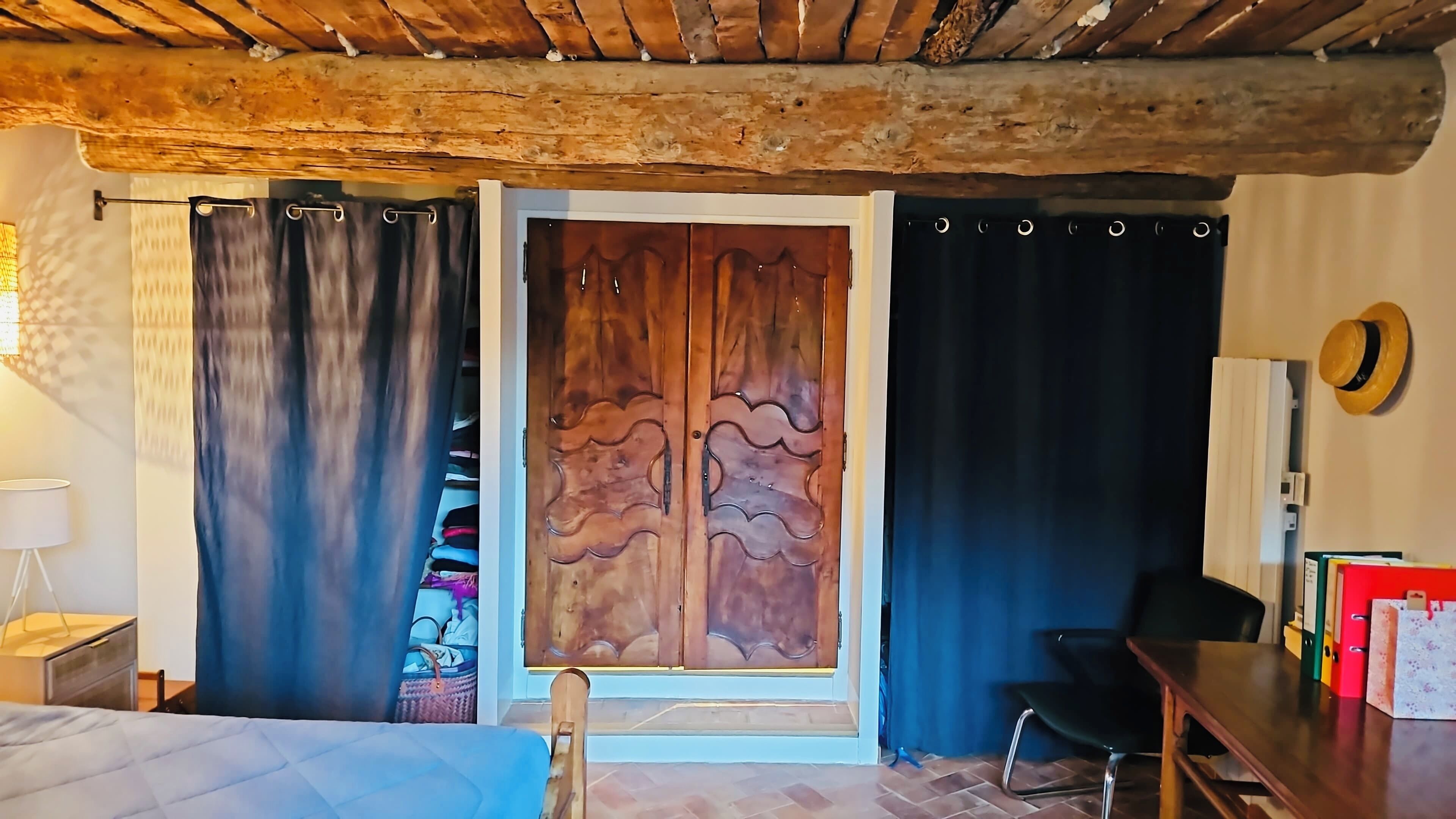 A room with a bed, a wooden wardrobe, a desk, and a chair.