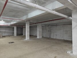 A spacious indoor area with concrete pillars, exposed pipes, and a clean floor.
