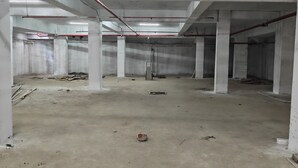A large, unfinished interior space with concrete floors and columns, exposed pipes, and minimal lighting. - Hotel Gokul Inn (Vapi)