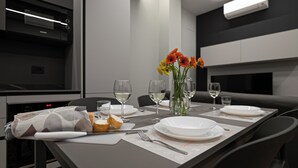 A modern dining room with a table set for two, featuring white plates, glasses, and a vase with flowers. - Italianway Comfort - Monte Nevoso 8 (Milan)