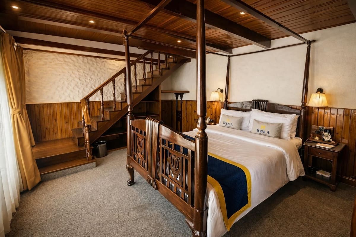 Ein Bett mit Baldachin und Holzrahmen, eine Treppe mit hölzernen Stufen und ein Nachttisch mit einer Lampe.