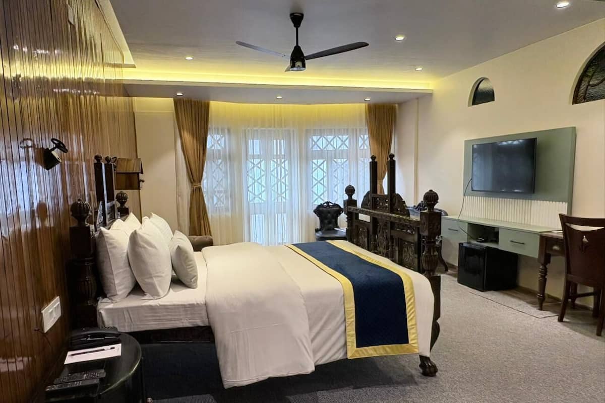 Ein Hotelzimmer mit einem großen Bett, einem Schreibtisch, einem Fernseher und einem Deckenventilator.
