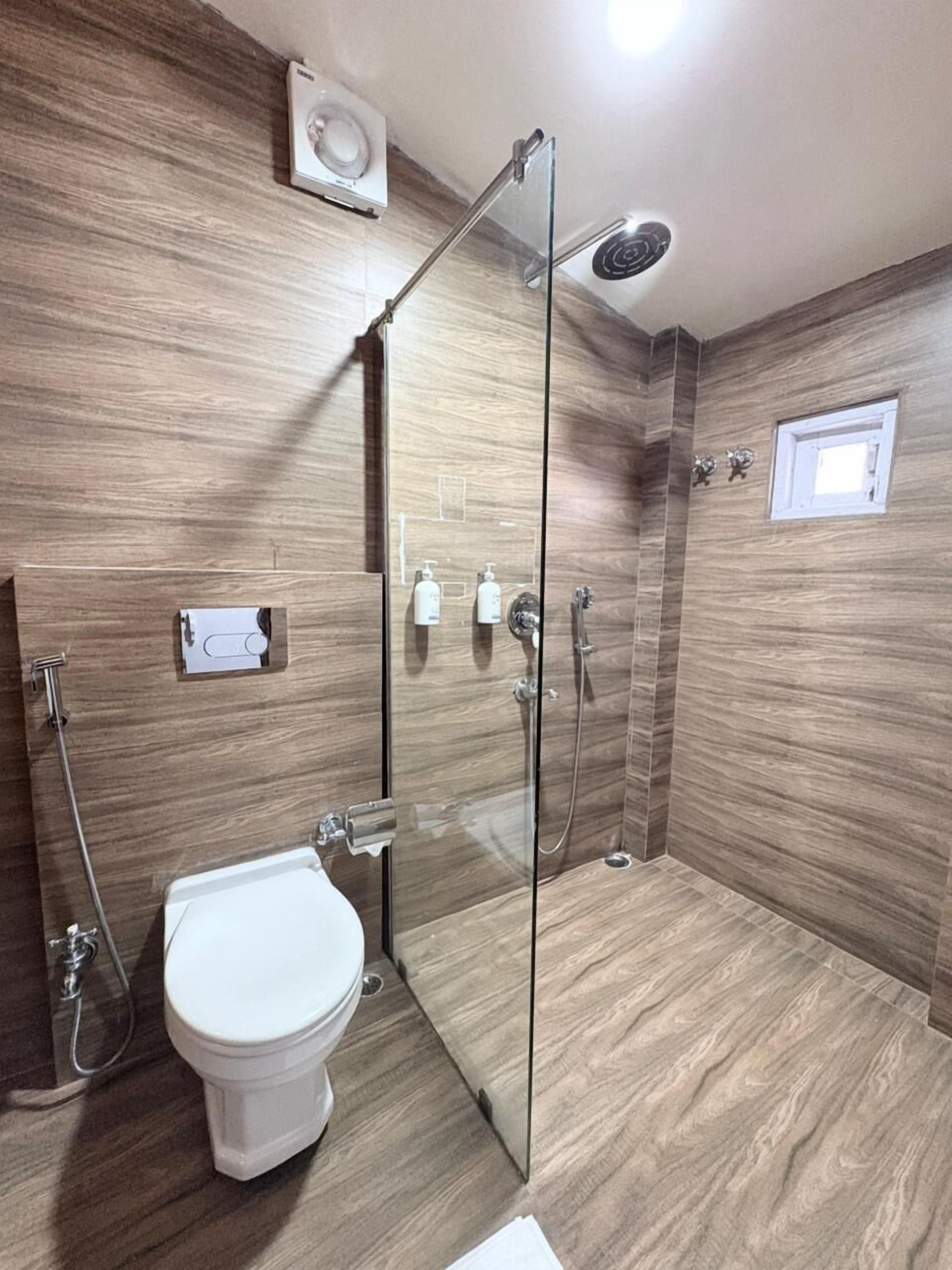 A modern bathroom with a glass-enclosed shower, a toilet, and a bidet.