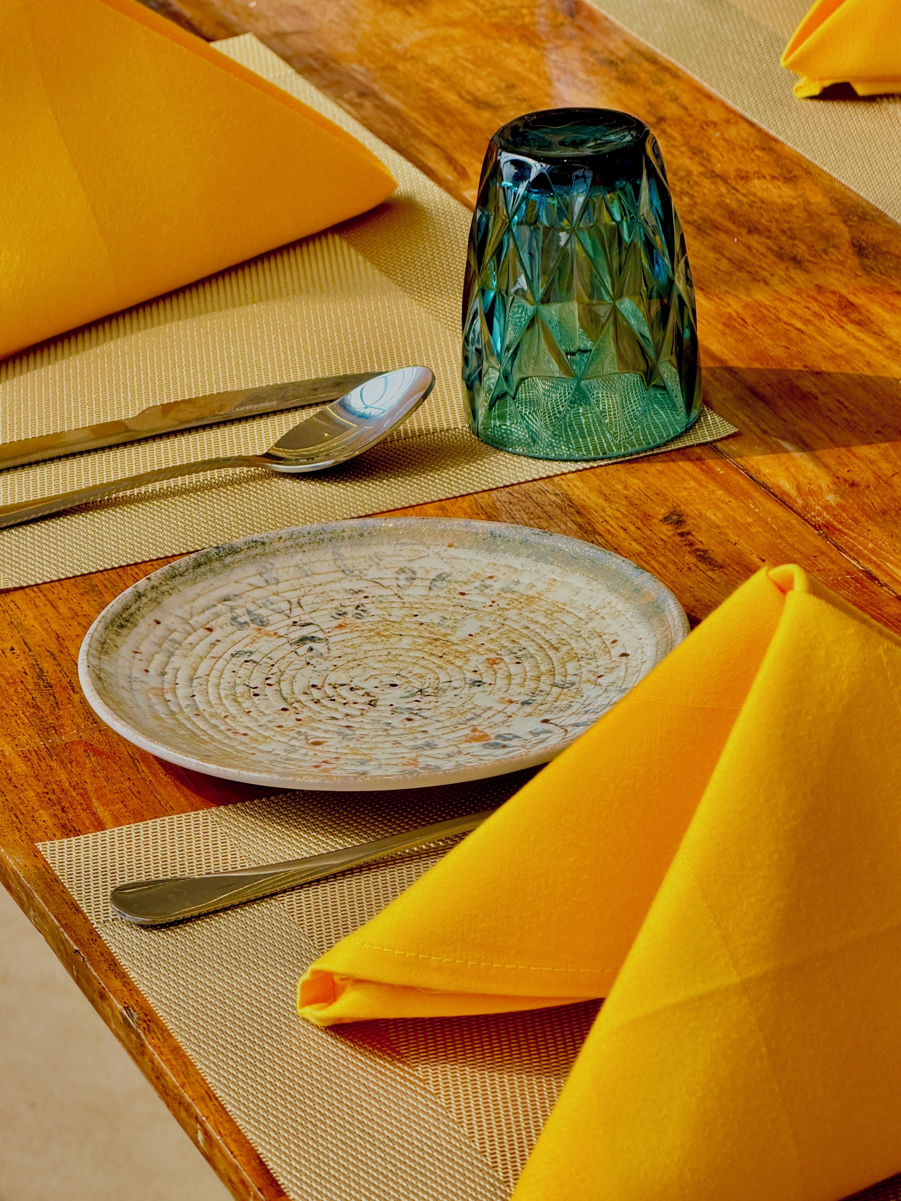 A dining table with a plate, utensils, a glass, and a napkin.
