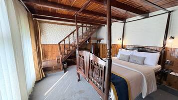 Ein Bett mit Baldachin, ein Holzkopfteil, eine Holztreppe und Blick auf eine strukturierte Wand.