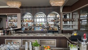 Zona de bar con una variedad de botellas de licores, vasos y utensilios.