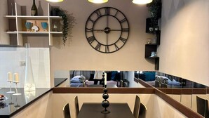 Una cucina moderna con isola centrale, luci a sospensione e un grande orologio a parete.